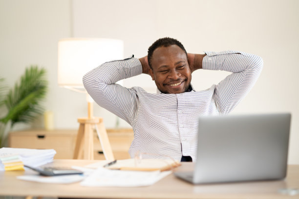 办公室职员愉快地微笑着舒适地坐在办公桌旁休息图片下载