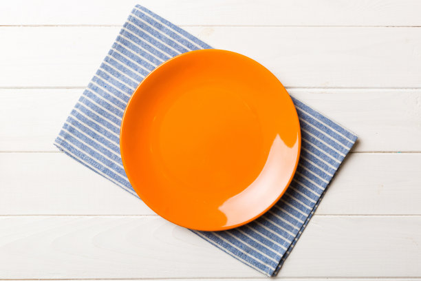 彩色背景上的俯视图，在桌布上放食物的红色空圆盘。空盘子放在餐巾上，为你的设计留出空间图片下载