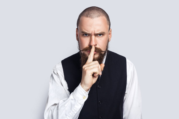 严肃严厉的男人站着，摆出嘘的姿势，带着专横的表情看着镜头。图片下载