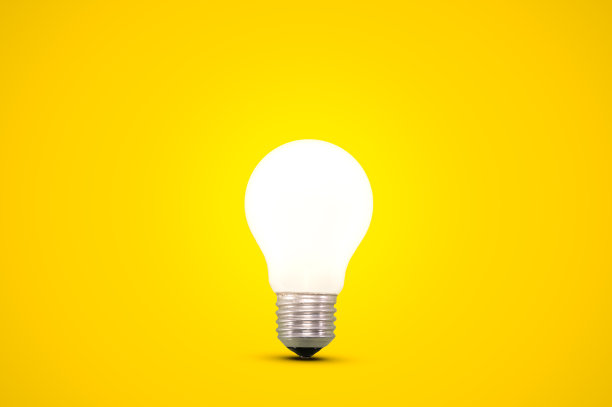 明亮的黄色背景上孤立的发光灯泡。图片下载