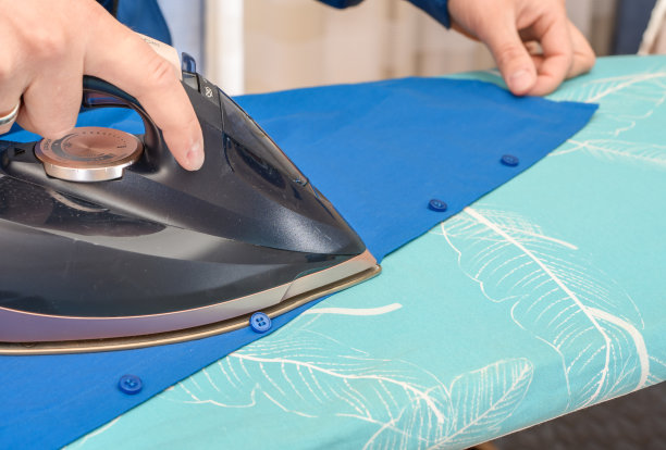 一个男人在熨衣板上熨衬衫图片下载