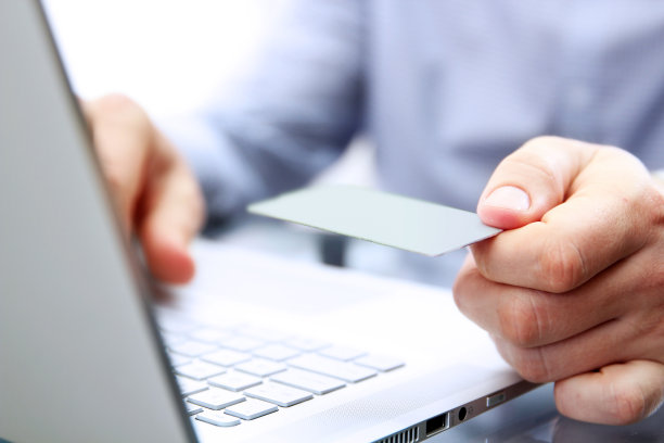 这个人在笔记本电脑上用信用卡付款。顾客在网上购物时用信用卡付款。图片下载