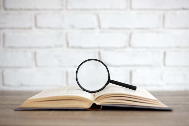 阅读、教育和研究理念——打开书本，用放大镜放在桌子上，在白色砖墙背景上复制空间图片下载