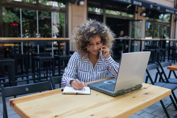 漂亮的年轻女子留着非洲式发型，正在咖啡馆用笔记本电脑工作。图片下载