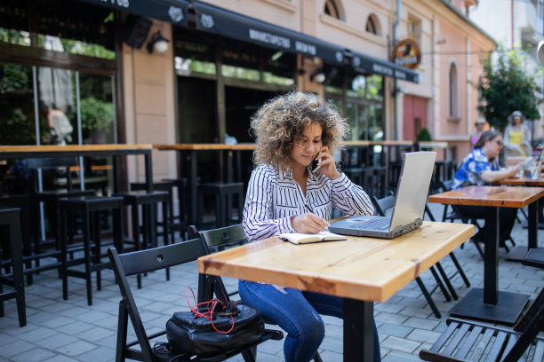 漂亮的年轻女子留着非洲式发型，正在咖啡馆用笔记本电脑工作。图片下载