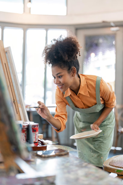 非裔美国女艺术家在画布上画画，在她的工作室里做一些艺术项目图片下载