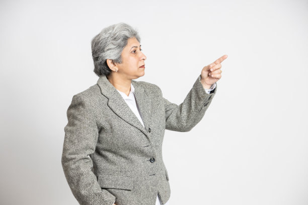 微笑、自信、成熟的印度资深女性用手指着空白的广告或促销空间。亚洲中年女商人，60多岁白发苍苍的女士执行业务领导经理。图片下载