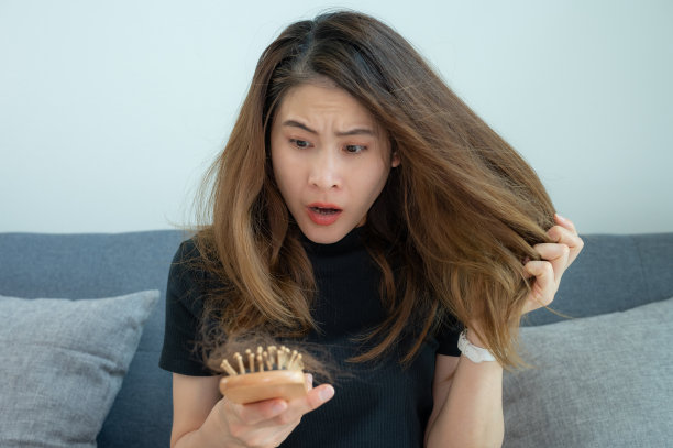 一名忧心忡忡的女子在梳头后看到自己的头发脱落后感到震惊。图片下载