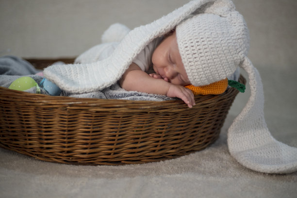 可爱的复活节小兔子。小男孩带着兔子耳朵和复活节彩蛋在柳条篮子里图片下载