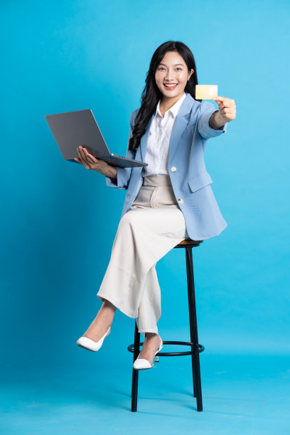 亚洲女商人肖像坐在椅子上，孤立的蓝色背景图片下载