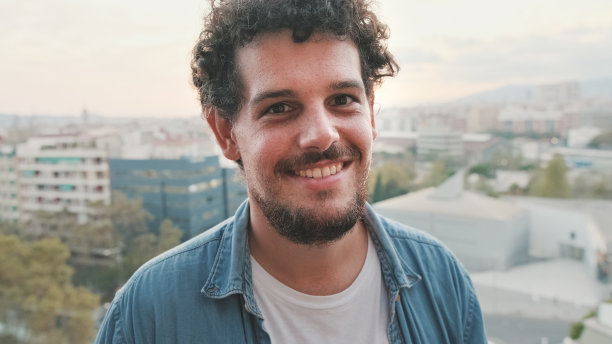 站在阳台上微笑的年轻人对着镜头摆姿势的特写图片下载