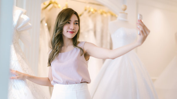 新娘和新郎在商店挑选结婚礼服。新娘和新郎选择礼服，并尝试在现代婚礼工作室图片下载