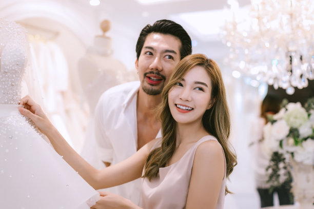 新娘和新郎在商店挑选结婚礼服。新娘和新郎选择礼服，并尝试在现代婚礼工作室图片下载