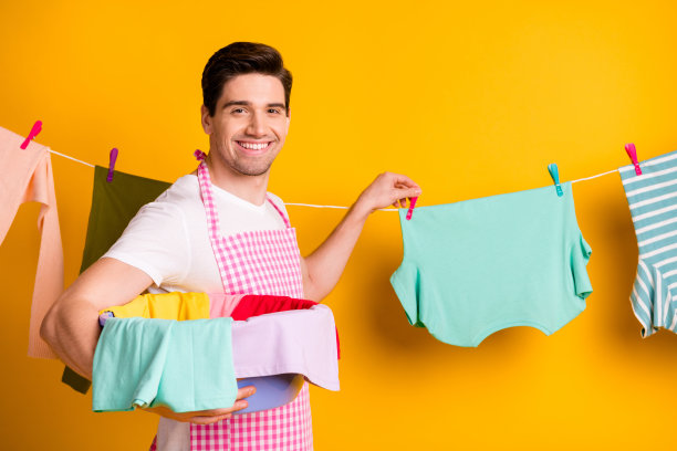 年轻快乐的好心情的照片微笑开朗的人抱着盆与干净的衣服隔离在黄色的背景图片下载