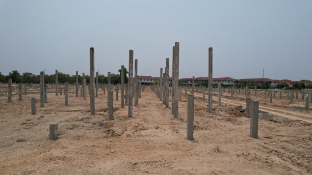 许多灰色的垂直钢筋混凝土柱在一个工业设施的施工现场，蓝天为背景，基础设施新建图片下载