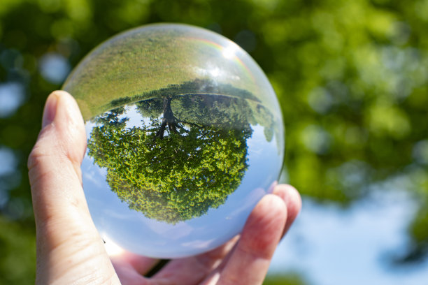 斯堪的纳维亚的自然和树的外部和内部。关注自然和气候，将自然包裹在一个发光的水晶球中。球是用一只手拿的。图片下载