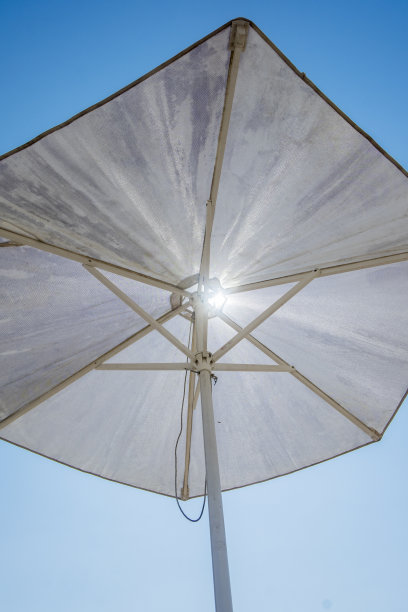 白色的遮阳伞映衬着深蓝色的天空，暗示着佛罗里达炎热的夏日。图片下载