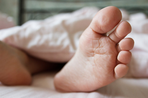 脚盖在床上的薄毯子下。健康的概念图片下载