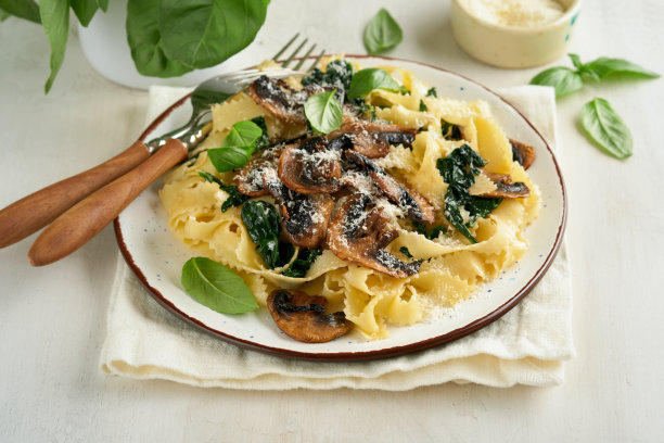 奶油阿尔弗雷多意大利面。意大利意式宽面，加蘑菇、鸡肉、菠菜、罗勒和奶油酱，背景为白色石头或混凝土。传统的意大利菜。平的。本空间图片下载