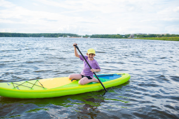 一个10岁的男孩独自在河上或湖上玩SUP板图片下载