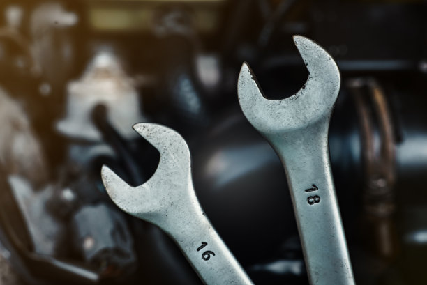 以汽车发动机为背景的扳手特写镜头。汽车商店或汽车修理店背景图片下载
