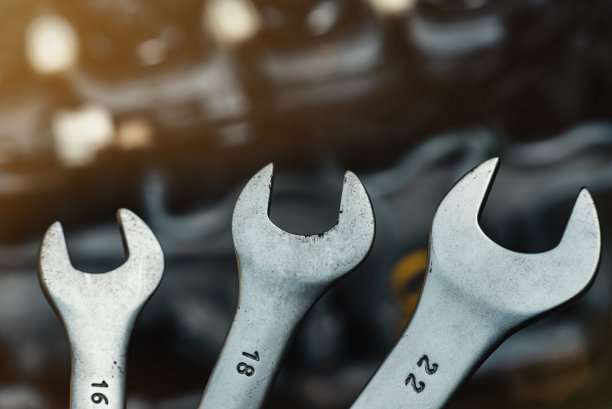 以汽车发动机为背景的扳手特写镜头。汽车商店或汽车修理店背景图片下载