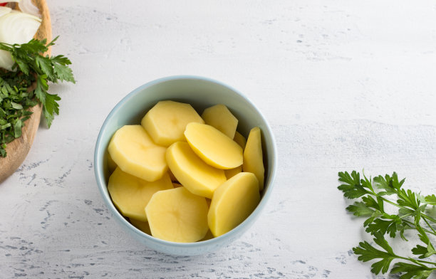 一碗土豆片，欧芹和洋葱碎，浅灰色背景，俯视图。烹饪美味的自制食物图片下载