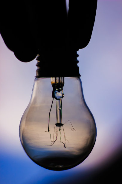 在夜空的背景下，一个灯泡的轮廓握在手里图片下载