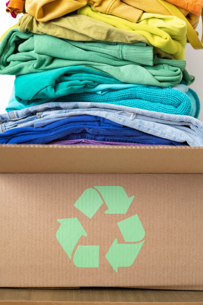 一堆不同颜色的衣服放在一个有回收标志的盒子里。图片下载