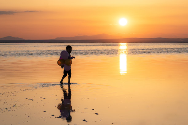 日落时分，孩子在盐湖边散步，玩得很开心。图片下载