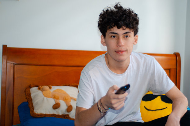 十几岁的男孩拿着电视遥控器看电视图片下载