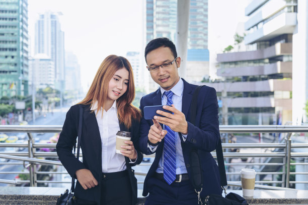 商人女商人在办公室外用智能手机在城里喝咖啡。手拿咖啡杯，手拿智能手机，一起聊着咖啡图片下载