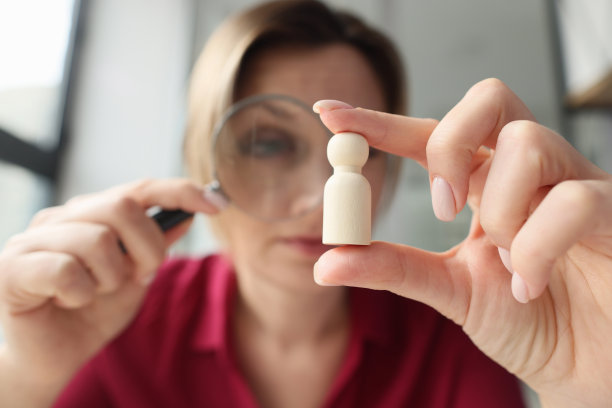 一名妇女通过放大镜观看木雕图片下载