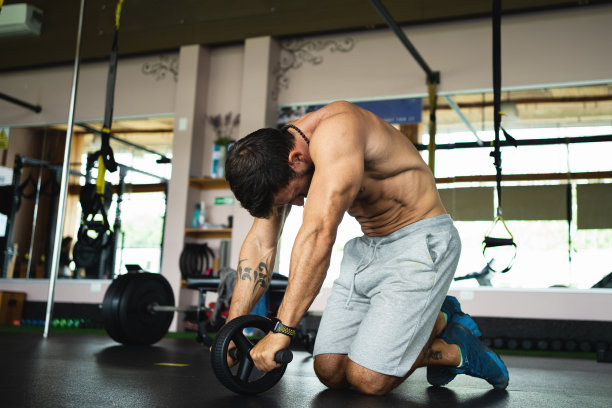 在健身房里使用腹肌轮的疲惫男子图片下载