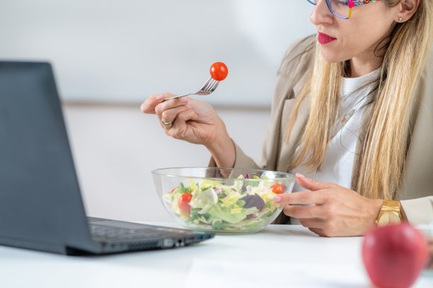 在工作场所吃新鲜沙拉的女人图片下载