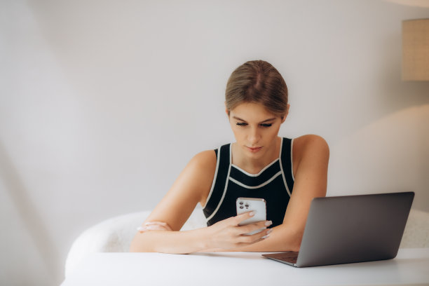 可爱的年轻女士的照片拿着电话，看屏幕，手掌键盘，戴着眼镜，在家里办公室，在室内图片下载