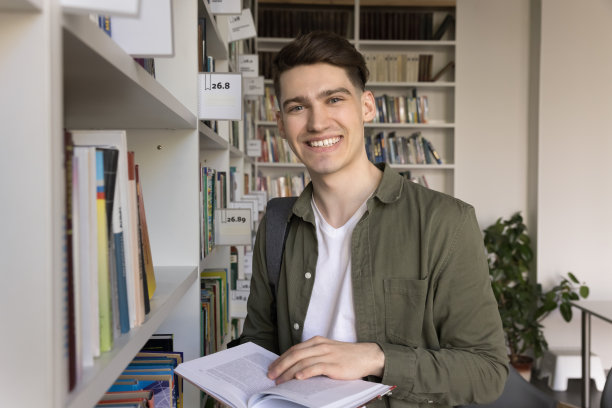 男学生在图书馆看镜头，拿着教科书摆姿势图片下载