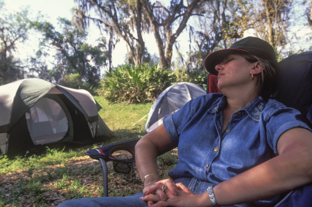 一名妇女睡在帐篷旁的露营地上图片下载