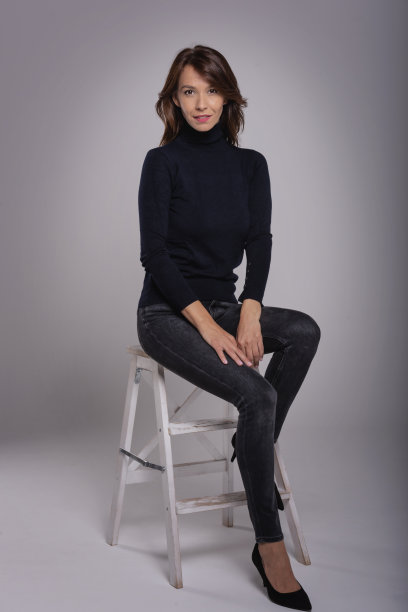 迷人的中年女人坐在孤立的灰色背景下图片下载