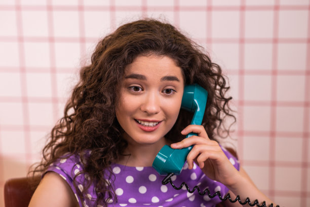 在厨房的镜头前，迷人的女士带着完美的微笑在老式固定电话上讨论，她变得非常兴奋和快乐图片下载