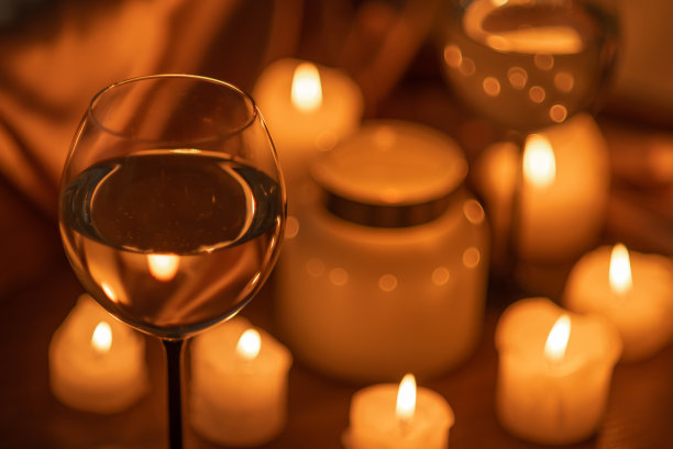 很多蜡烛在黑暗中燃烧，还有两杯白葡萄酒。浪漫的夜晚，约会。图片下载