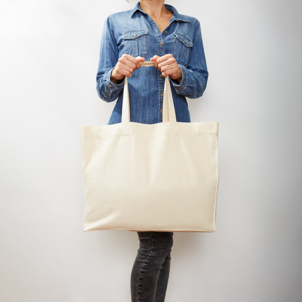 一个陌生的年轻女人，穿着牛仔衬衫，拿着一个空白帆布环保手提袋图片下载
