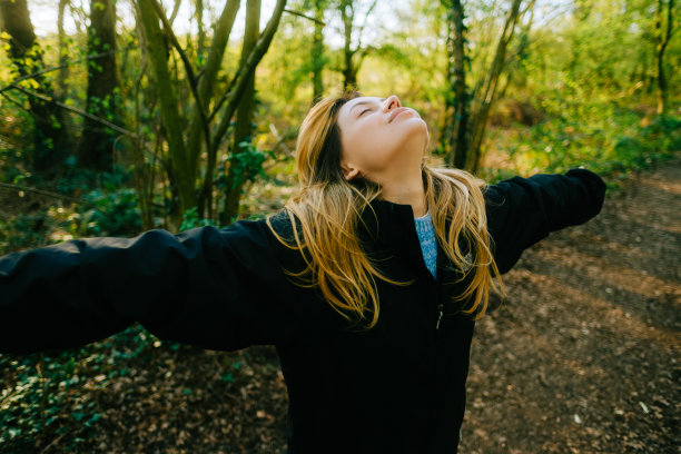 迷人的白人女性呼吸着新鲜的空气，在自然公园的日落中享受着春天图片下载