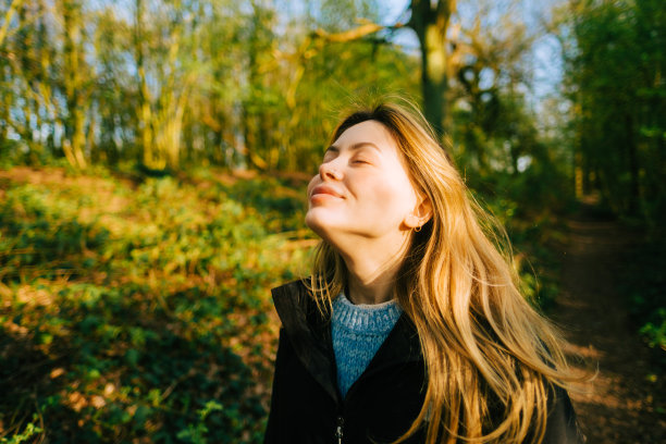 迷人的白人女性呼吸着新鲜的空气，在自然公园的日落中享受着春天图片下载