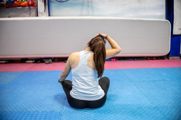 一个成熟的女人坐在健身房的运动垫上伸展身体图片下载