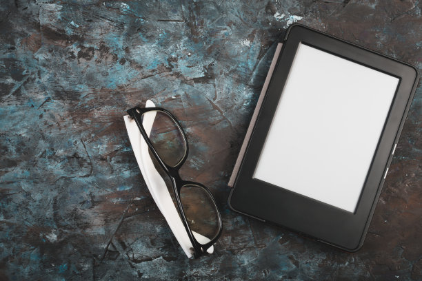 桌上有电子书和纸质书，还有一杯咖啡，一台笔记本电脑和老花镜。自我教育的概念。图片下载