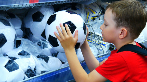 一个可爱的男孩在体育部挑选足球图片下载