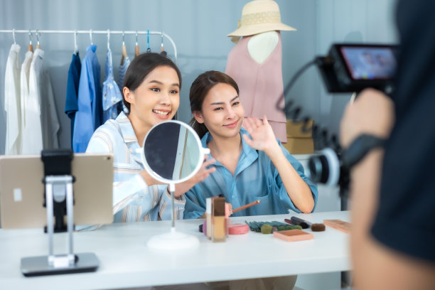 亚洲女性企业主在时装商店展示服装，在智能手机前录制视频视频直播，向顾客出售时装，网上购物概念。图片下载