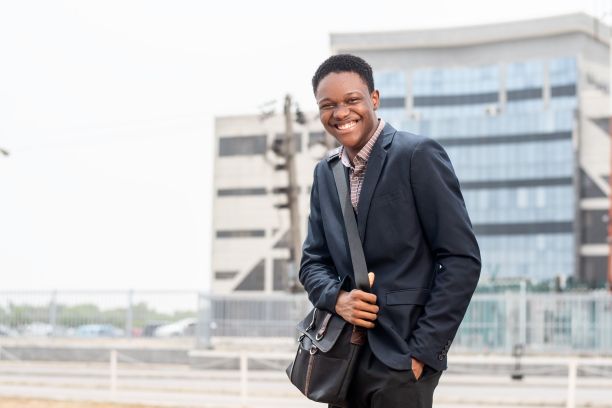 一个快乐的非洲年轻人站在城市街道上。图片下载