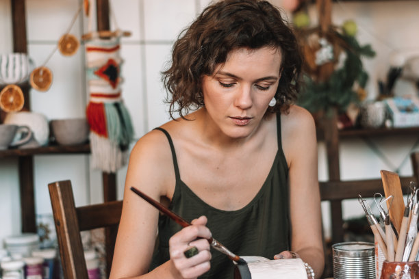 女雕刻家在家庭作坊里制作陶土，给陶土杯上釉。小生意、创业、爱好、休闲的理念图片下载